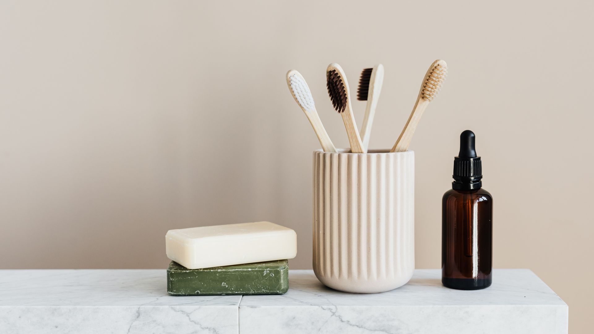 Luxury skincare morning ritual — amber dropper bottle on white marble shelf with bamboo accents and green botanical elements, clean editorial
