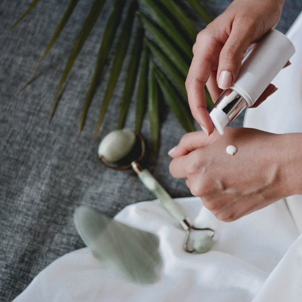 Customer lifestyle: woman applying cream to face, warm peachy background, morning skincare routine, authentic UGC aesthetic