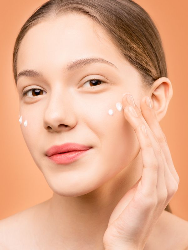 Step 3 Restore — person gently tapping cream beneath eye area with ring finger, dewy luminous skin, warm editorial light